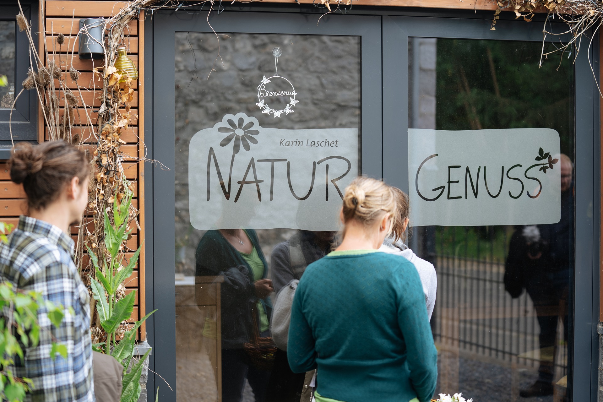 Vue de l'entrée de la cuisine de Karin Laschet. Sur la porte vitrée, on peut lire "Naturgenuss" en grosses lettres.