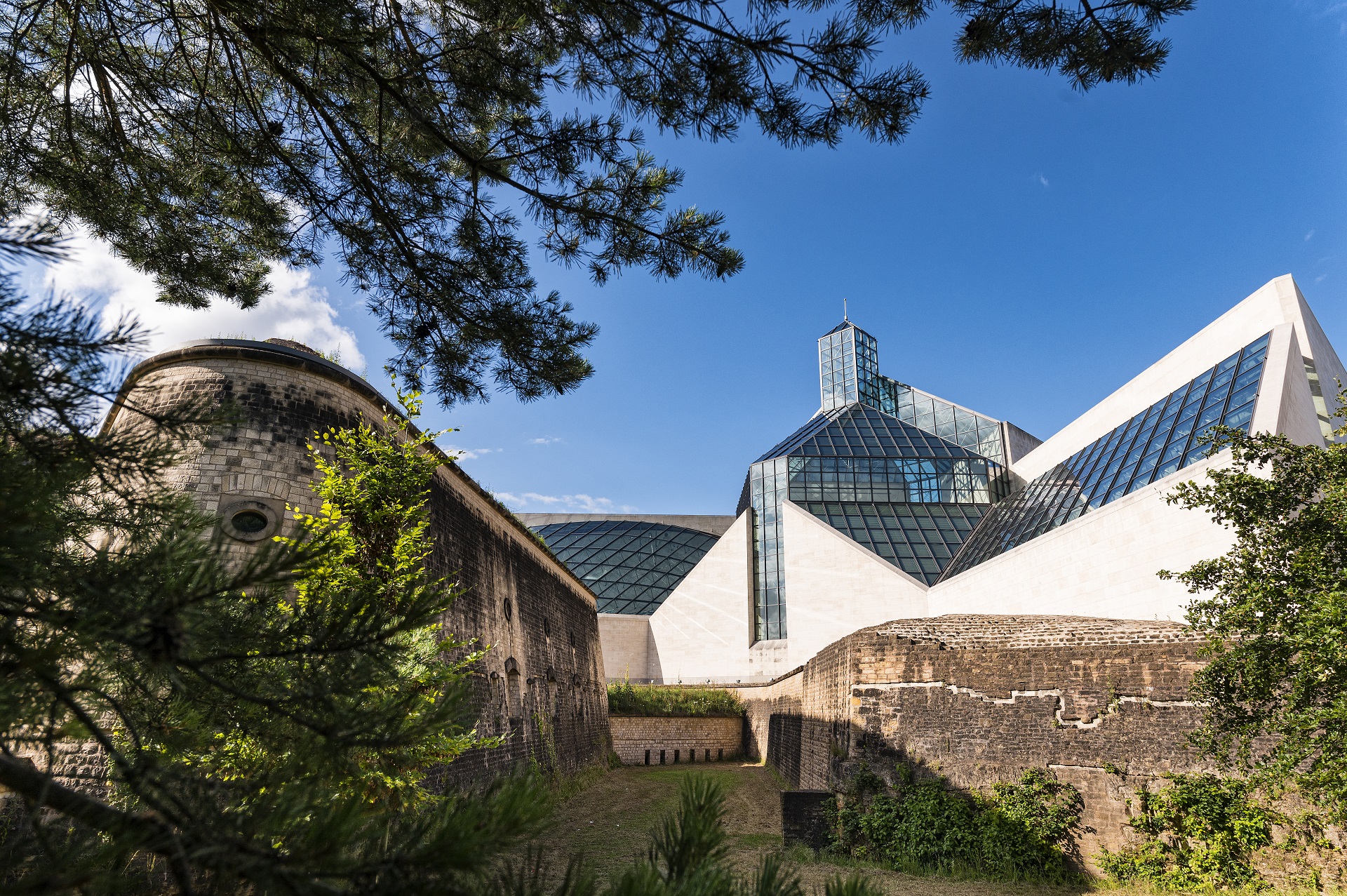 L'arrière du Musée d'art Mudam avec le Fort Thüngen et l'Oark "Dräi Eechelen". Le soleil brille et le ciel est bleu.