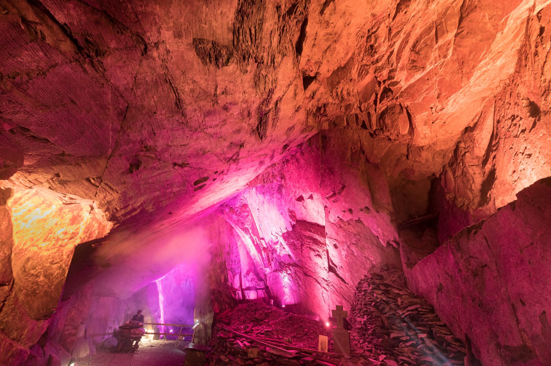 Dans les profondeurs du sous-sol, un spectacle de lumière a lieu. Des lumières roses et jaunes brillent dans la grotte minière.