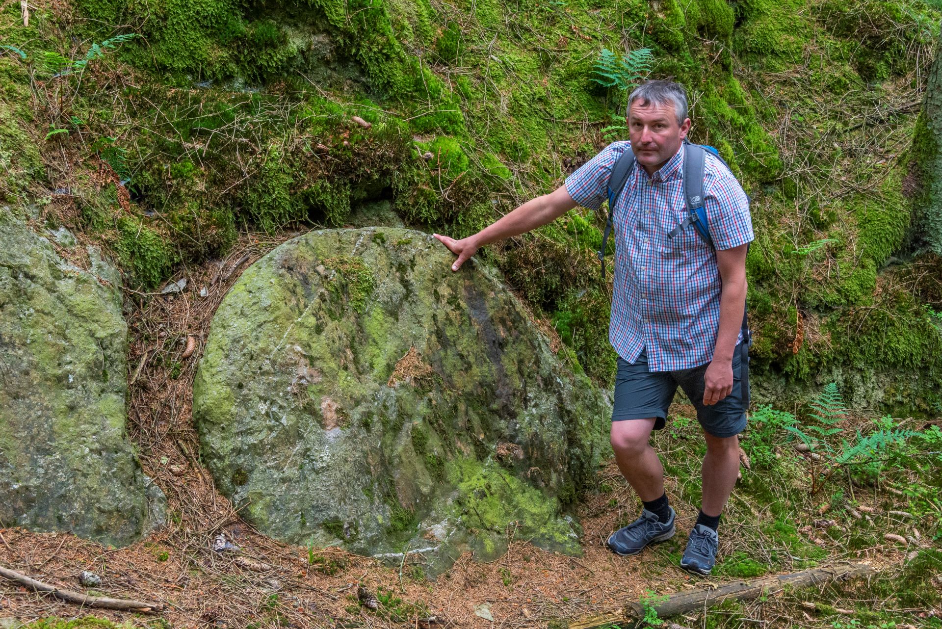 Le guide touristique appuie sa main sur une pierre ancienne qui a été façonnée en cercle par les Romains.