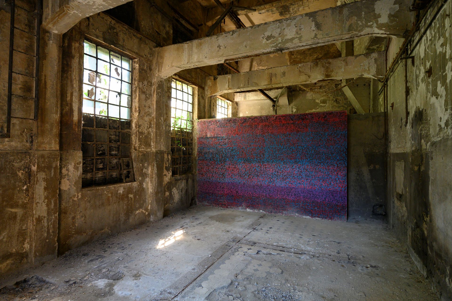 À l'intérieur de la hutte, une exposition d'art est présentée sous la forme d'un grand mur recouvert d'un motif abstrait et coloré.