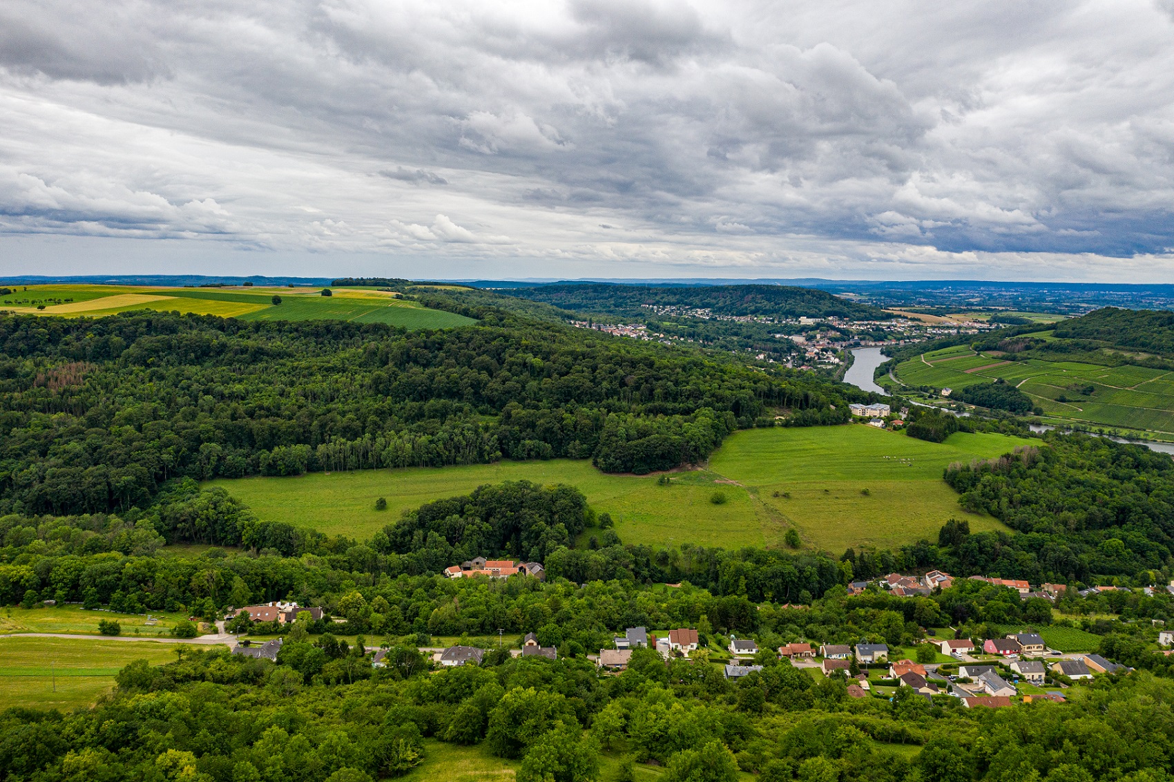 Photographie de paysage de la région de la Moselle. On peut voir des villages individuels dans la vallée. La rivière Moselle serpente en arrière-plan.