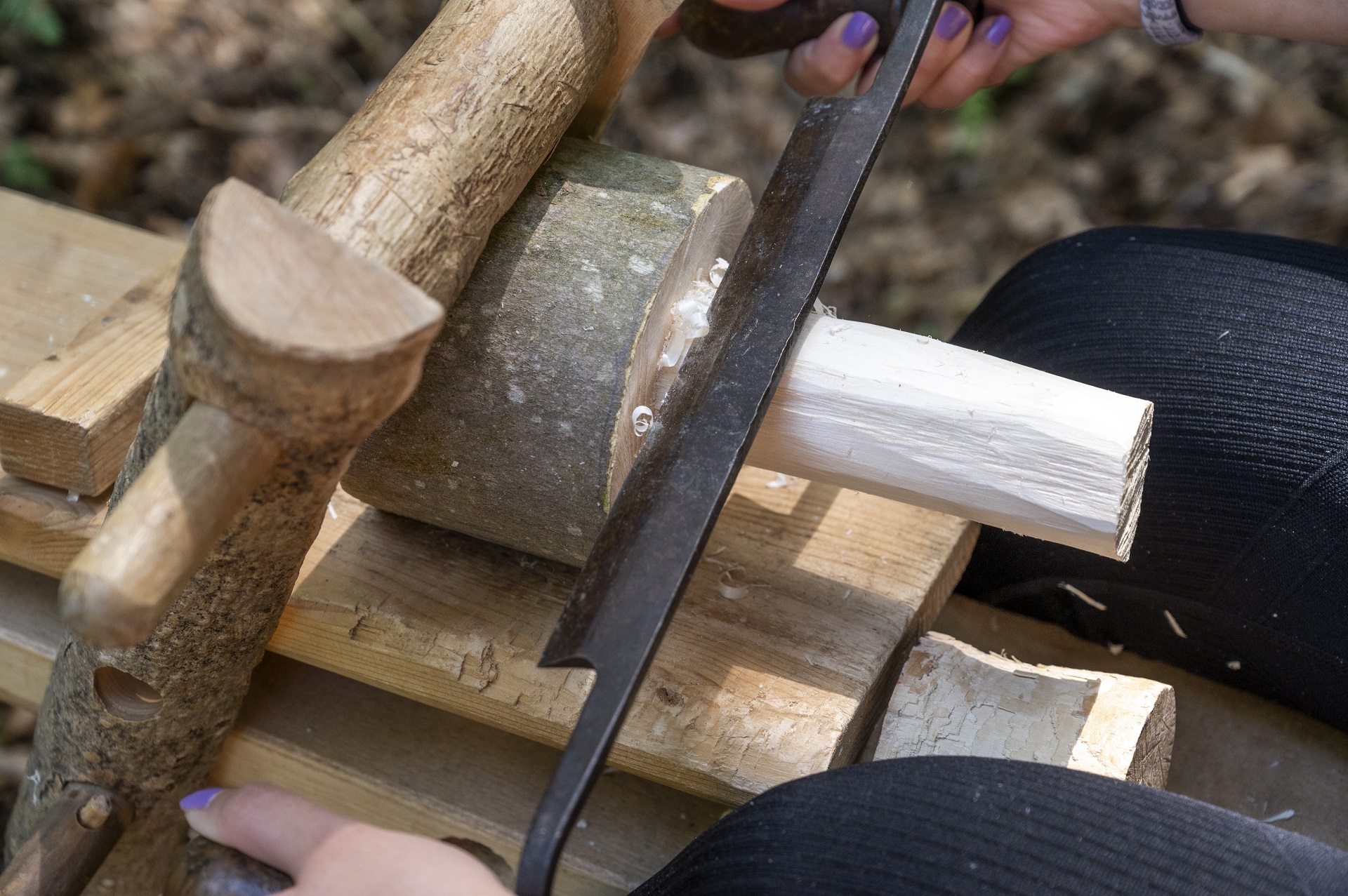 Gros plan d'un marteau en bois serré sur lequel une personne travaille.