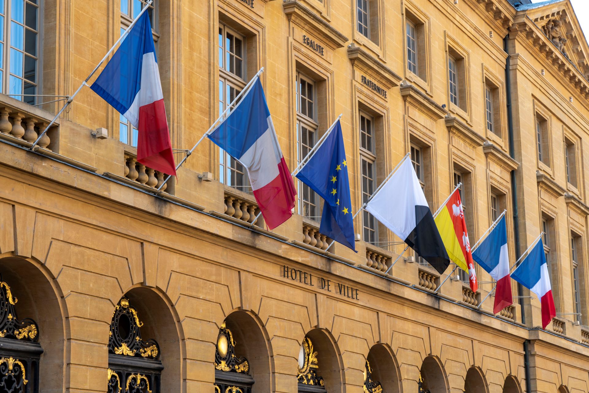 Les drapeaux de la France, de l'UE et de diverses provinces sont accrochés sur le côté jaune de l'Hôtel de Ville.