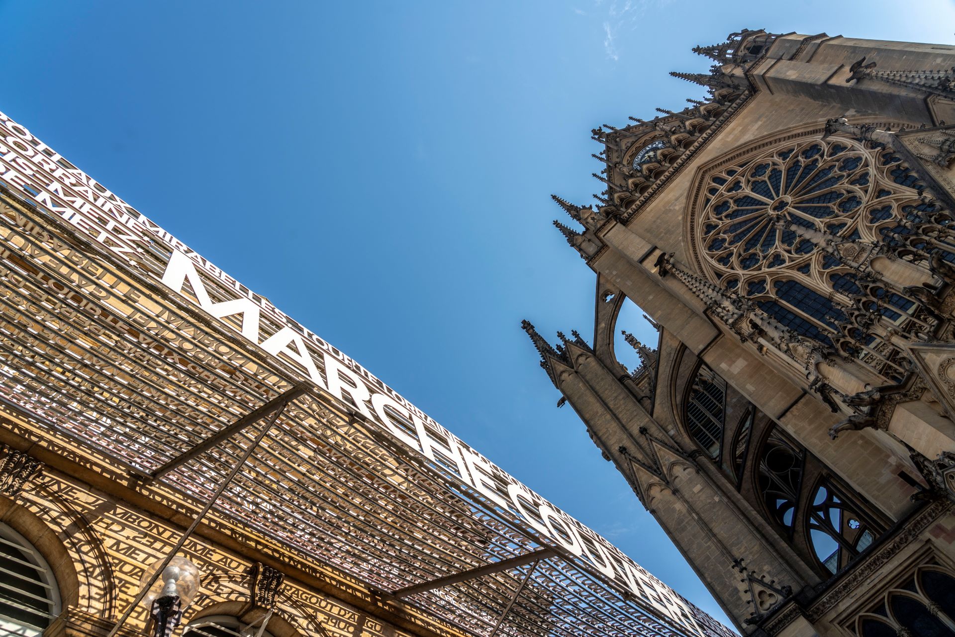 Sur l'une des places principales de Metz, on trouve l'entrée d'une halle de marché devant une ancienne cathédrale.