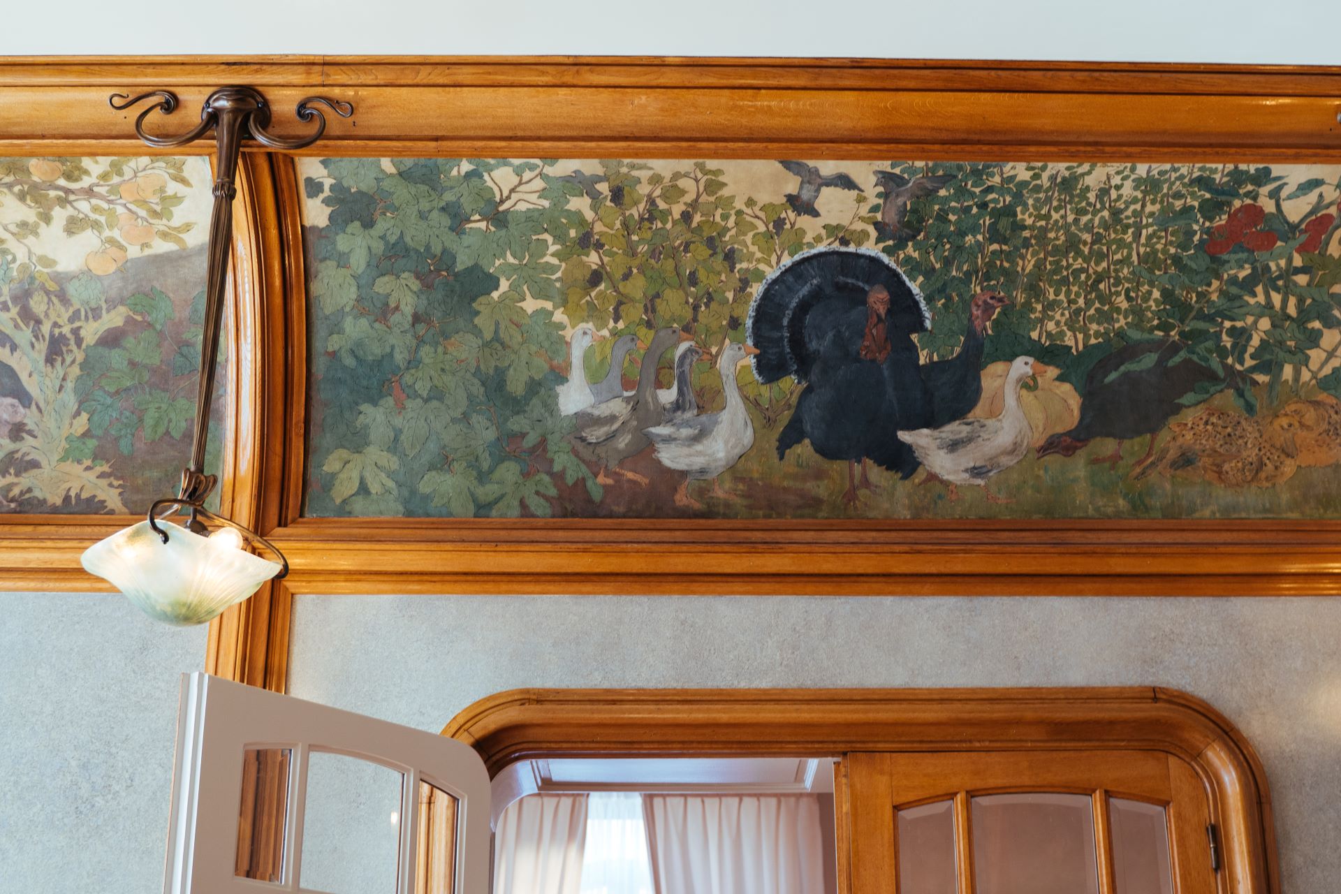 À l'intérieur du bâtiment, l'influence de la nature se fait clairement sentir. Un vieux tableau montre une volée d'oiseaux sauvages, et le tableau est entouré de formes naturelles en bois.