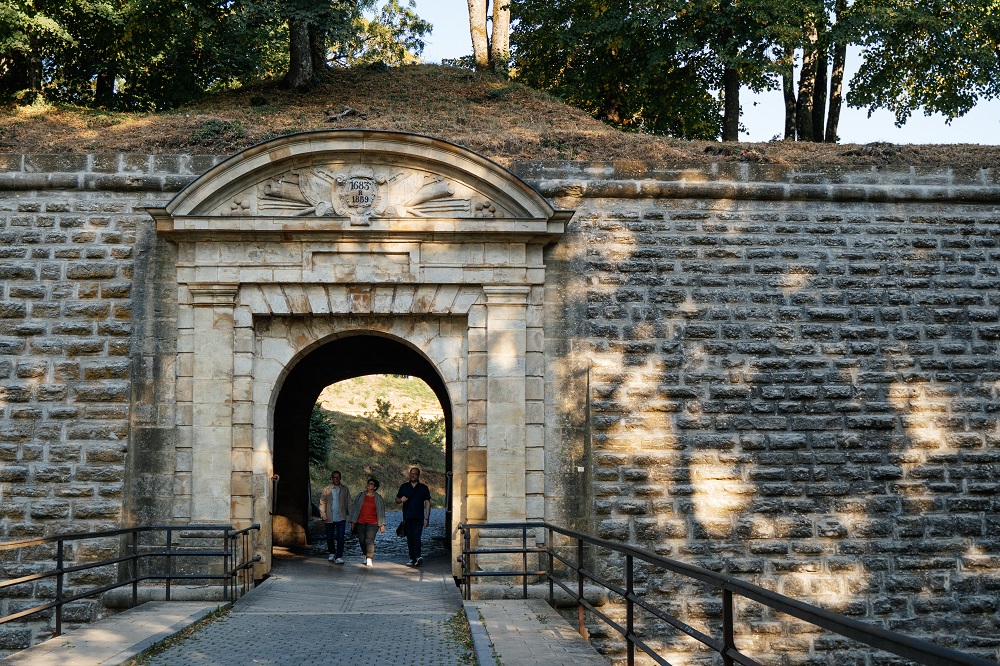 Trois personnes entrent à l'intérieur de la forteresse par la porte.