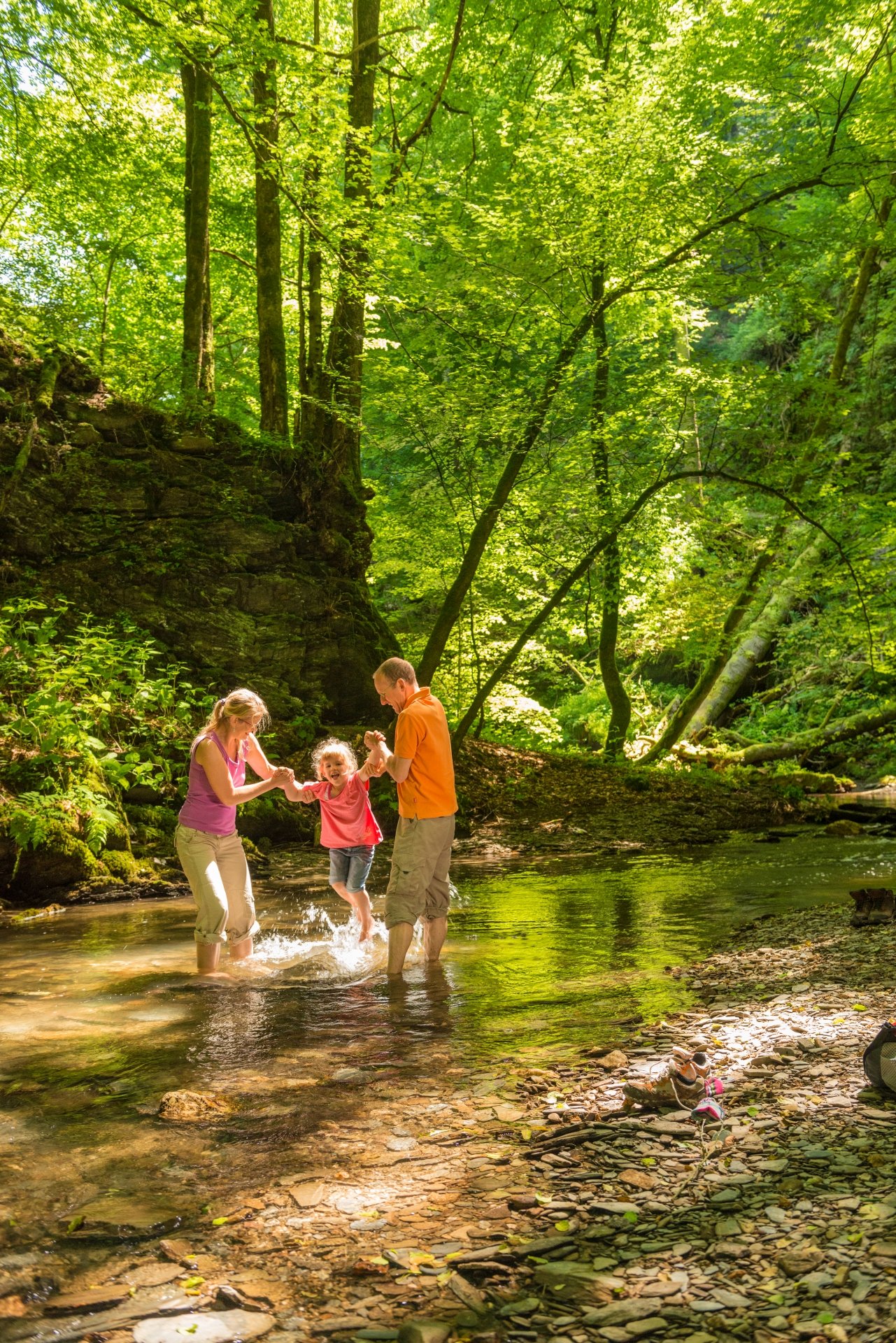 Une famille se rafraîchit dans un ruisseau en forêt lors d'une randonnée.