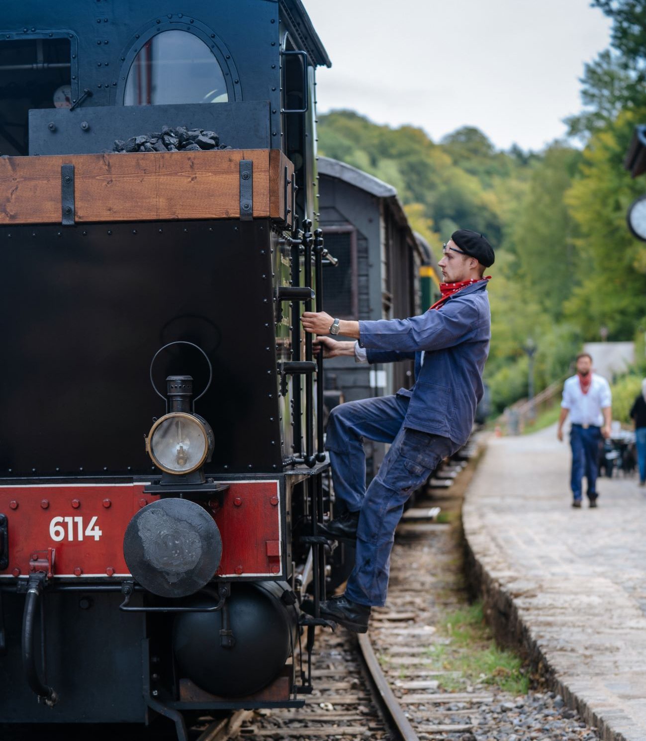 Ein als Zugführer verkleideter Mann hängt an der Seite eines historischen Zuges. Der Zug scheint sich zu bewegen.