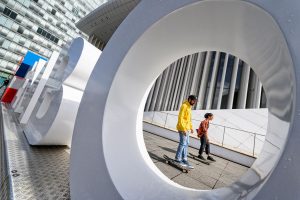 Eine große Kunstinstallation im Freien, auf der das Wort "Luxemburg" zu lesen ist, zeigt zwei Skateboarder, die im Hintergrund zu sehen sind und durch einen der Buchstaben hindurch aufgenommen wurden.