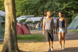 Ein Paar spaziert bei Sonnenschein über den Campingplatz.