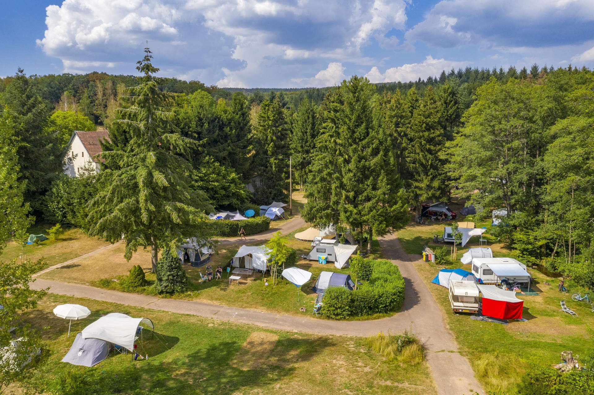 Eine Luftaufnahme des Campingplatzes mit Zelten und Campingmobilen.