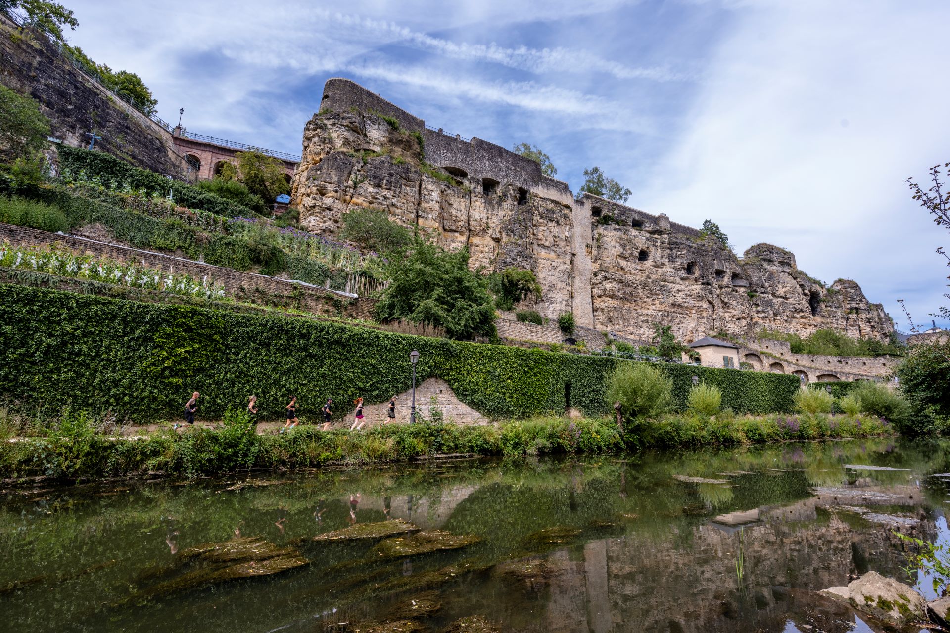 Blauer Himmel und grünes Moos heben die Überreste der Festung Luxemburg hervor, die man vom kleinen Fluss unterhalb der Festungsmauern aus sehen kann.