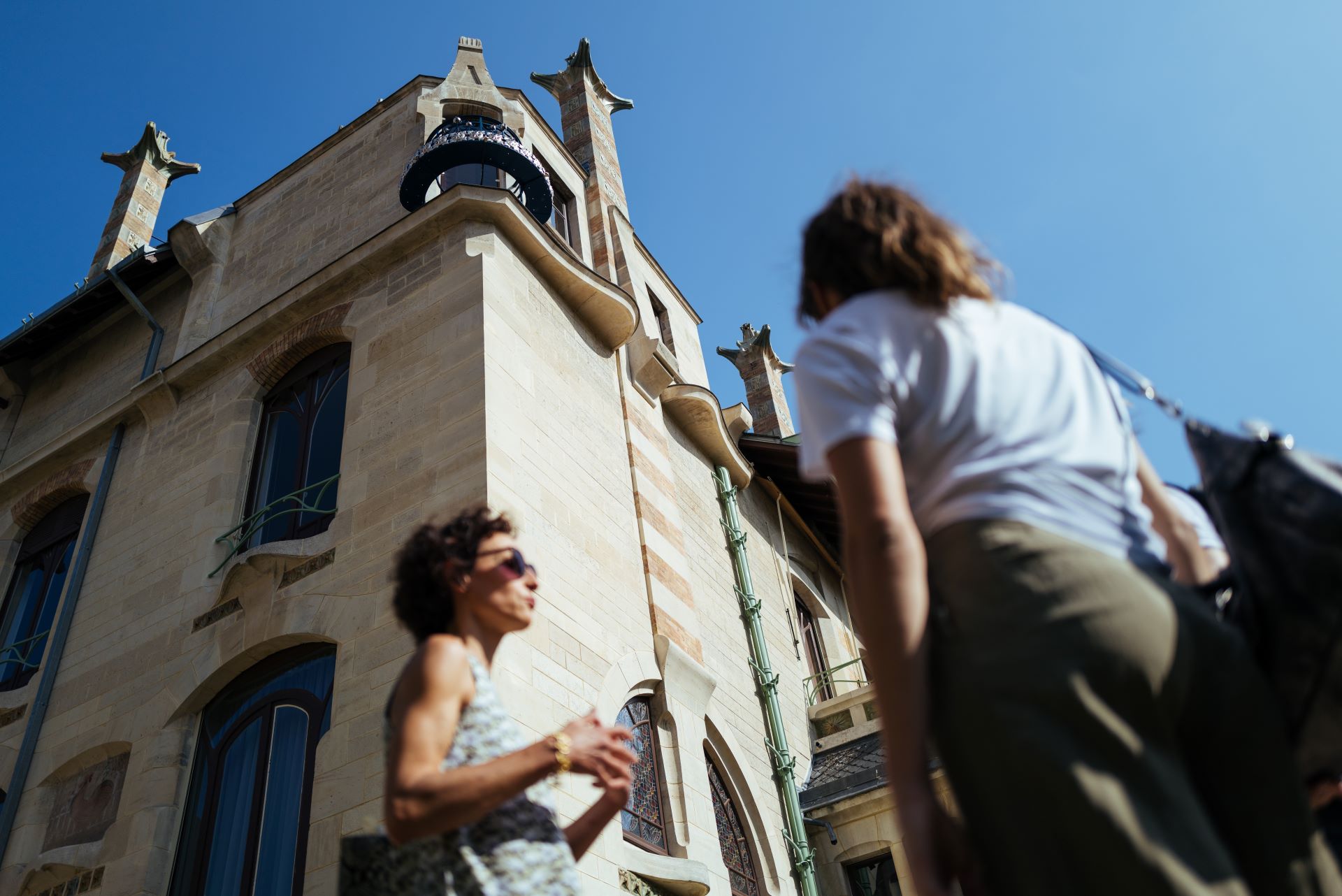 Draußen erklärt die Reiseleiterin ihren Gästen vor einem historischen Gebäude etwas.