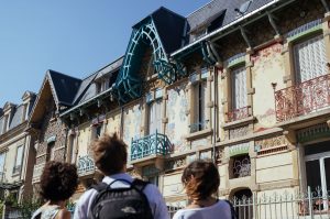 Auf der Straße zeigt die Fremdenführerin ihren Gästen die komplizierten Details an der Außenseite des Gebäudes.