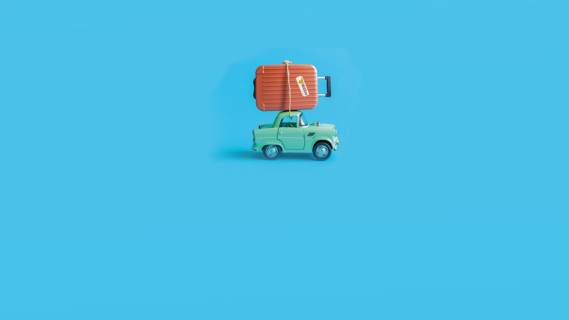 Mitfarbenes Auto mit braunem Koffer samt Großregions-Logo auf dem Koffer vor blauem Hintergrund.