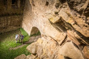 Ein Wanderpaar betrachetet den Innenhof der Klosterruine Disibodenberg